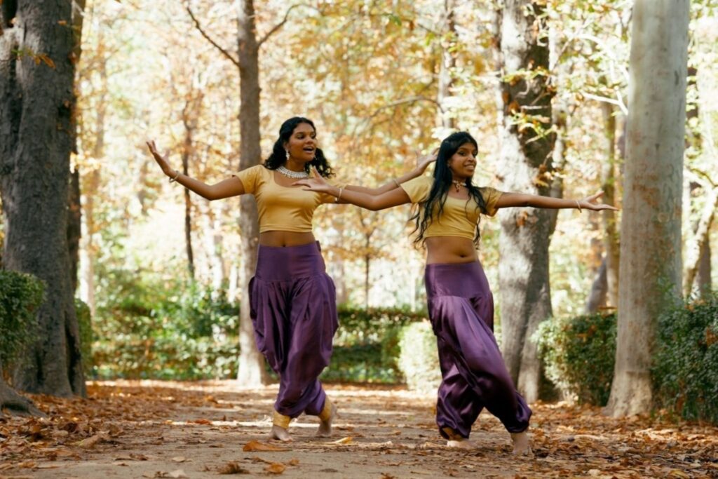 दो दोस्त बाहर शास्त्रीय कला नृत्य सीख रहे हैं जो पारंपरिक भारतीय नृत्य शिक्षा और सांस्कृतिक पुनरुद्धार को दर्शाता है