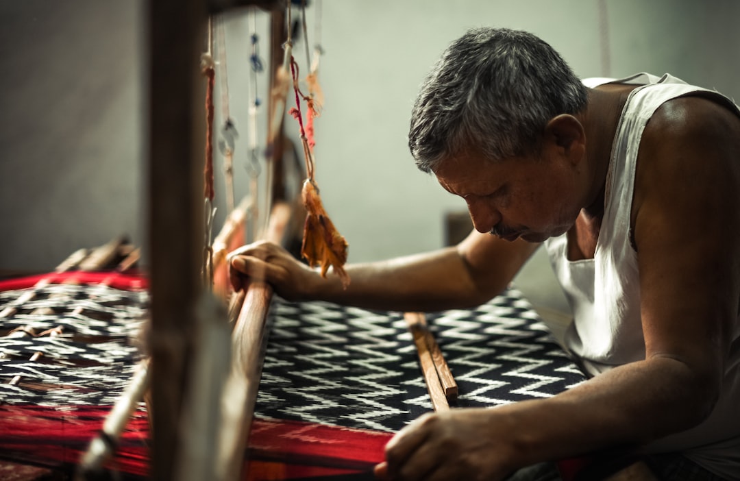 A Indian artisan weaves khadi on a handloom, showing the tradition behind ethical fabrics that are ideal for the monsoon.