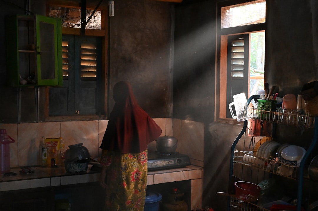 An Indian woman switching on a kitchen exhaust fan to improve ventilation as a key step to monsoon proof her home.