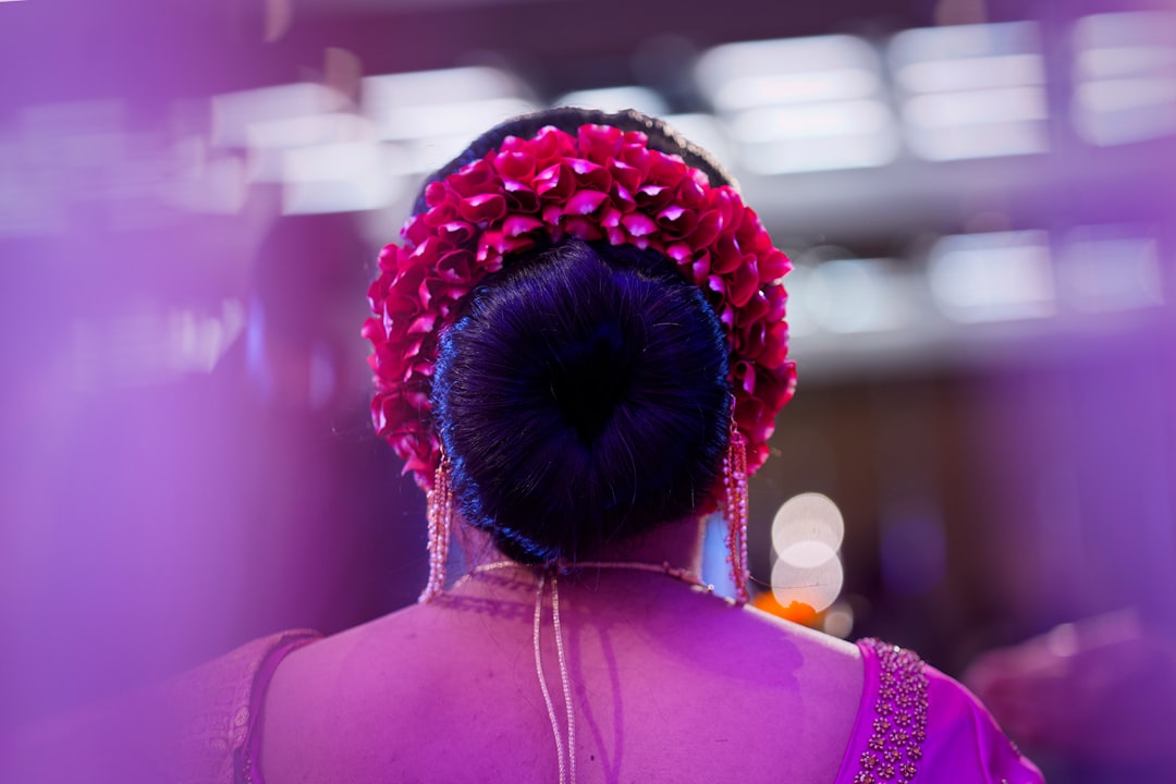 An Indian woman styling her monsoon hair into a protective bun using a wooden comb
