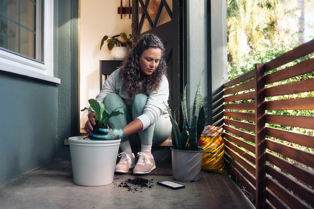 An Indian woman using finished composting soil to feed potted herbs on their apartment balcony