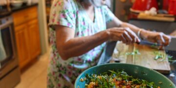 woman-composting-kitchen-scraps-unsplash - INDIAwebzine A young Indian woman sorting vegetable peels into a composting bin in her apartment kitchen