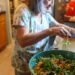 woman-composting-kitchen-scraps-unsplash - INDIAwebzine A young Indian woman sorting vegetable peels into a composting bin in her apartment kitchen