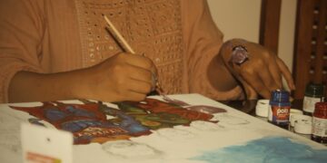 woman-painting-folk-art-paper-unsplash - INDIAwebzine A woman carefully creating a Madhubani painting on thick white paper with a fine-tipped brush