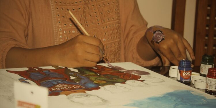 Une femme créant avec soin une peinture Madhubani sur du papier blanc épais avec un pinceau à pointe fine