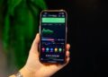 A young Indian woman checks her index funds portfolio on a smartphone at a modern desk