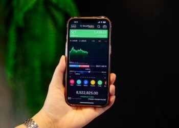 A young Indian woman checks her index funds portfolio on a smartphone at a modern desk