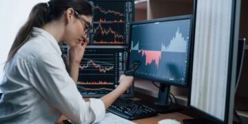 A focused Indian woman reviewing her sovereign gold bonds portfolio on a laptop at her office desk