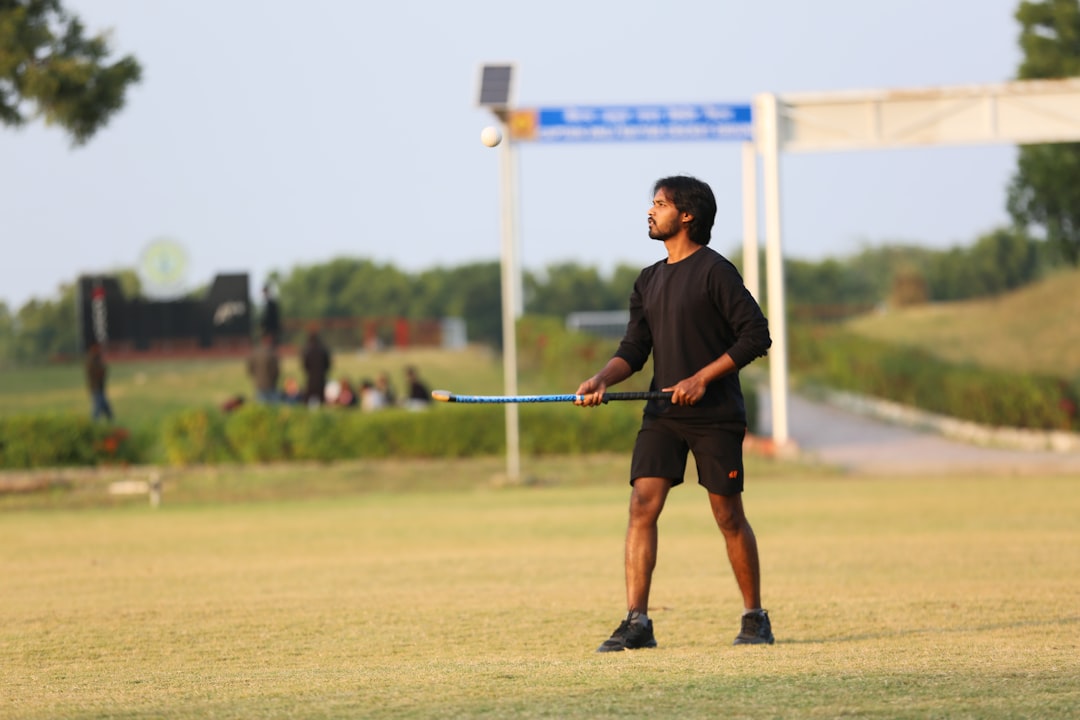 A young boy prepares to strike a Gilli with a Danda while playing traditional Indian games in an open field
