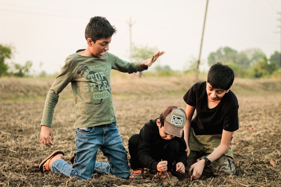 Two children competing in Indian games with glass marbles on a sunny outdoor surface