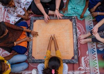 A grandmother teaches her grandchild how to play traditional Indian games on a wooden board at home