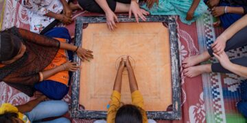 A grandmother teaches her grandchild how to play traditional Indian games on a wooden board at home