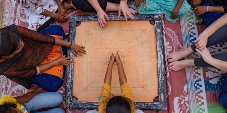 A grandmother teaches her grandchild how to play traditional Indian games on a wooden board at home