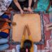 A grandmother teaches her grandchild how to play traditional Indian games on a wooden board at home