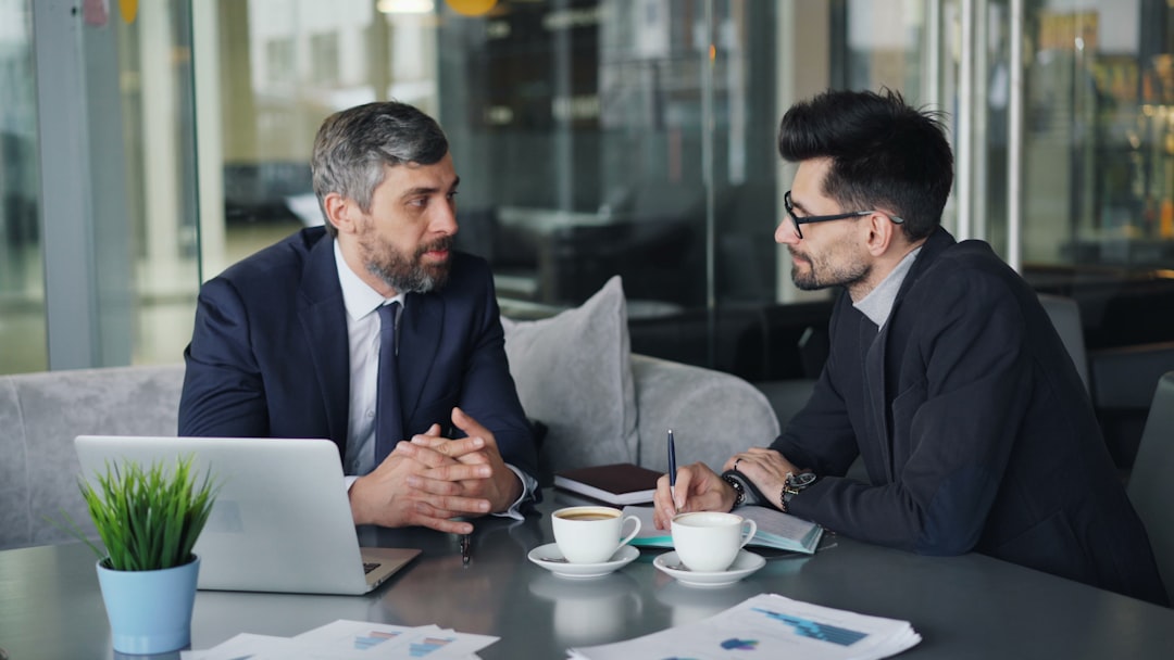 Two professionals discuss a pitch deck during a meeting, reflecting how startup funding decisions now extend.