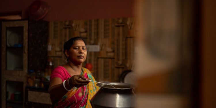 A grandmother teaches her granddaughter a traditional recipe, showing how the Indian diaspora passes culinary heritage.