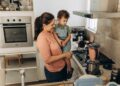 A mother and child performing science experiments at home using turmeric and bowls on a kitchen counter in India