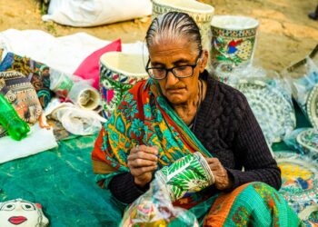 An Indian woman artisan reviewing handmade pricing beside her craft products