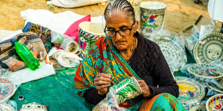An Indian woman artisan reviewing handmade pricing beside her craft products