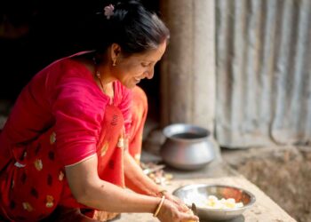 A woman in an Indian kitchen measuring gluten-free flours to prepare homemade flatbread