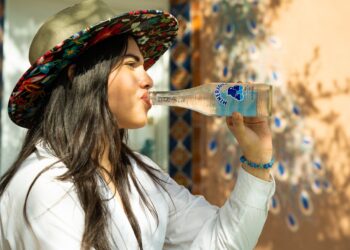 A young Indian woman drinking clean bottled water at a street market, protecting her gut health during monsoon season