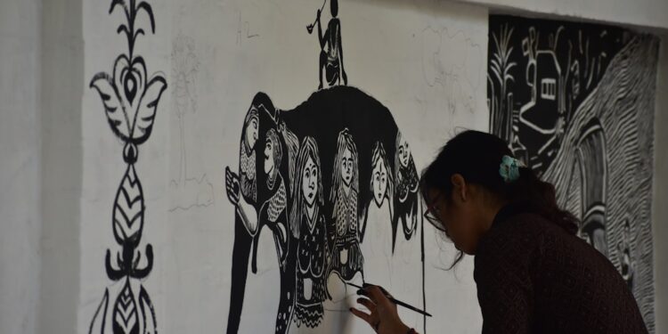indian-woman-painting-tribal-patterns-unsplash - INDIAwebzine A woman in Maharashtra creating Warli art on brown paper using traditional white paint and a fine brush