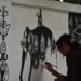 A woman in Maharashtra creating Warli art on brown paper using traditional white paint and a fine brush