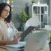 indian-woman-reading-financial-document-unsplash - INDIAwebzine A focused Indian professional woman reviewing an annual report at her desk before making her first equity investment