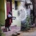 A woman using her rooftop rainwater harvesting setup during the monsoon season in an Indian home