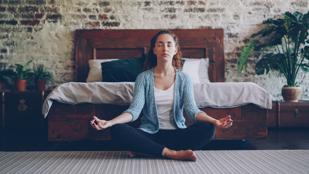 Indian woman doing pranayama breathwork near a sunny window as part of her morning work-from-home routine