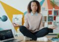 Indian woman practising pranayama breathwork at her home office desk with eyes closed