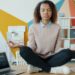 Indian woman practising pranayama breathwork at her home office desk with eyes closed