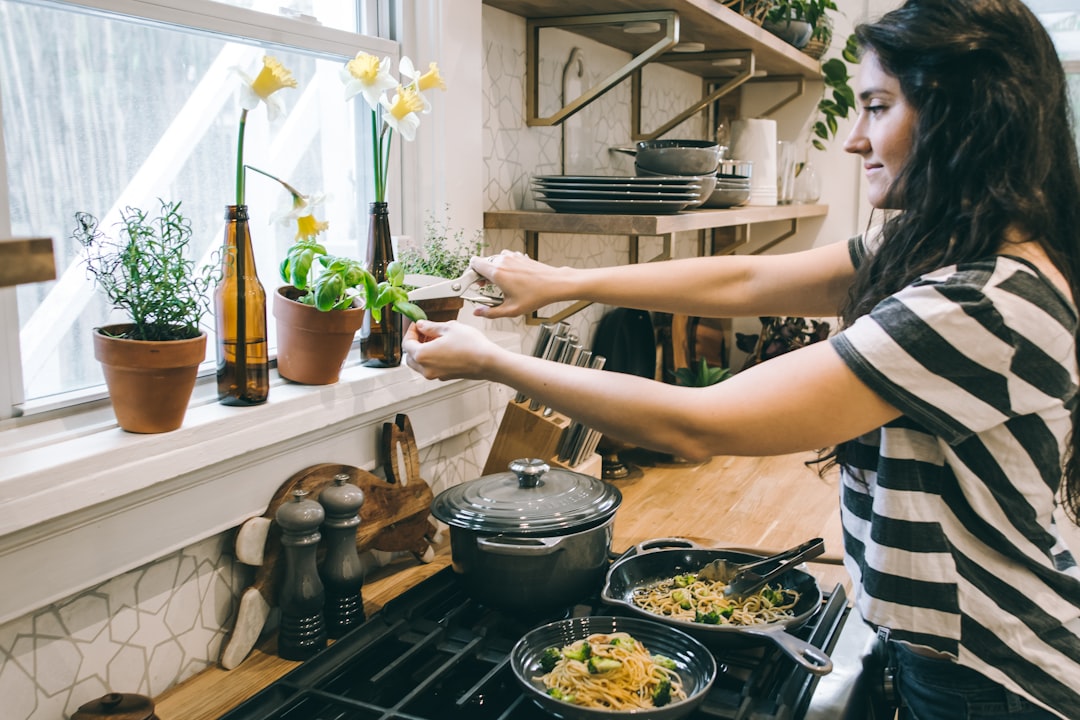 A woman using plant-based dishwash liquid at a kitchen sink as part of her plastic-free kitchen routine