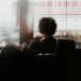 woman-reading-book-window-rain-unsplash - INDIAwebzine A woman sits in a cozy reading nook near a rain-streaked window, wrapped in a cotton throw, holding a book