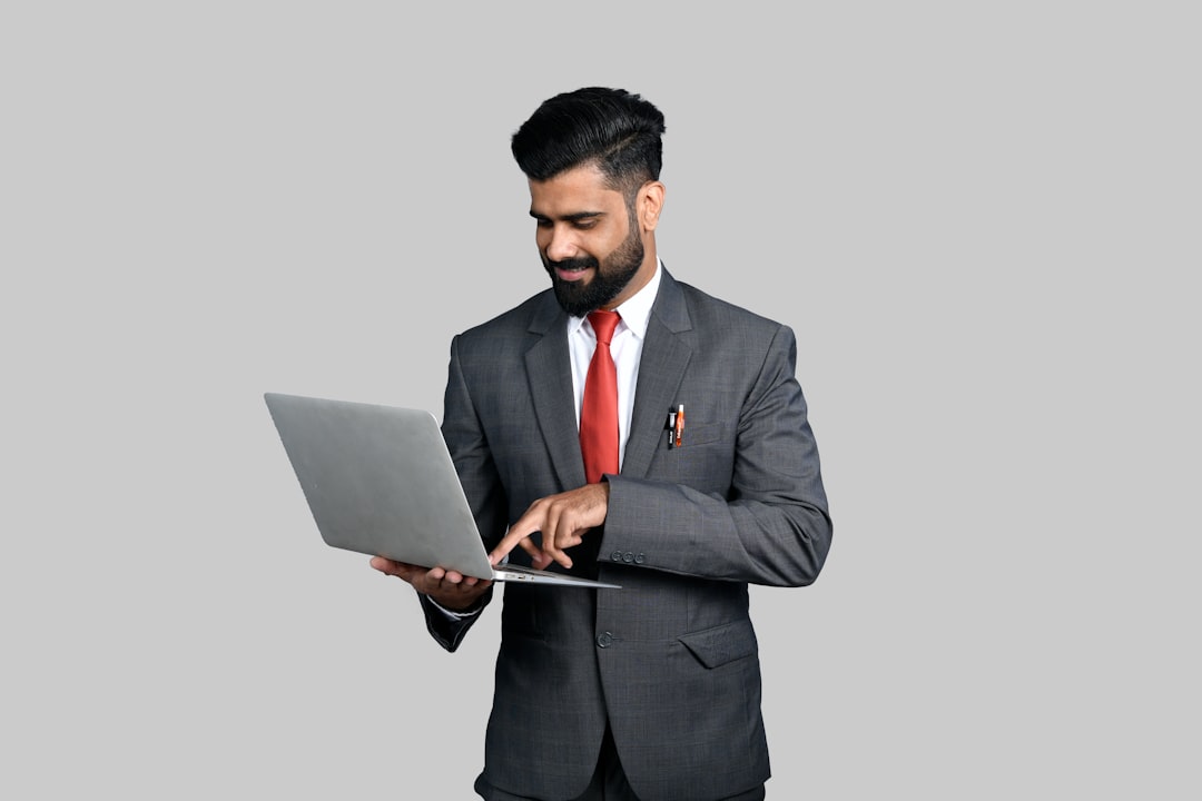 An Indian businessman submitting a trademark registration form online through the IP India portal on his laptop