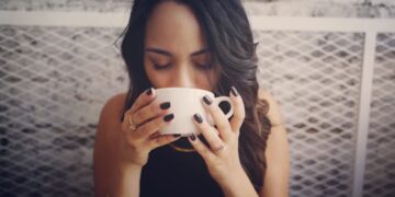 indian-woman-drinking-warm-herbal-tea-unsplash - INDIAwebzine A woman practicing monsoon wellness by drinking warm tulsi ginger tea at home in India