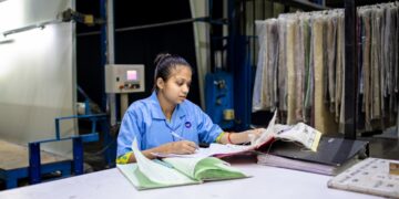 A young Indian woman entrepreneur completing her trademark registration application at a desk in a modern Mumbai office
