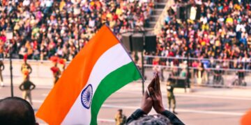 indian-woman-flag-ceremony-crowd-unsplash - INDIAwebzine A woman in traditional dress holds the Indian tricolour at an Indian diaspora Independence Day ceremony abroad.