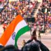 indian-woman-flag-ceremony-crowd-unsplash - INDIAwebzine A woman in traditional dress holds the Indian tricolour at an Indian diaspora Independence Day ceremony abroad.
