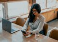 A young Indian professional woman reviewing mutual fund SIPs on her laptop at a modern home office desk