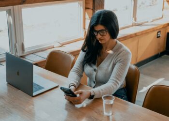 A young Indian professional woman reviewing mutual fund SIPs on her laptop at a modern home office desk