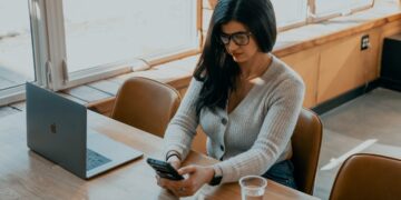 A young Indian professional woman reviewing mutual fund SIPs on her laptop at a modern home office desk