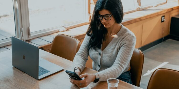 indian-woman-investor-laptop-phone-unsplash - INDIAwebzine A young Indian professional woman reviewing mutual fund SIPs on her laptop at a modern home office desk