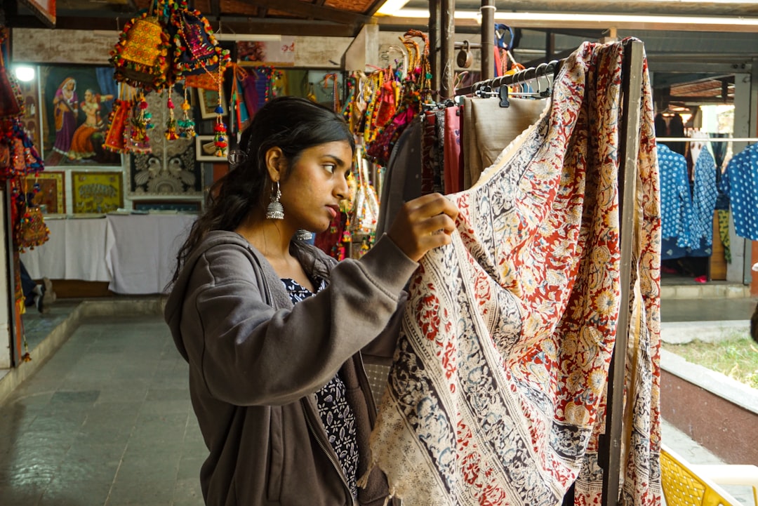A woman examining breathable fabric at a textile store, selecting materials for her next monsoon outfits