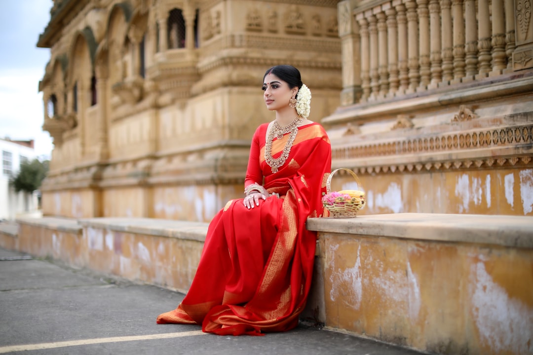 A woman in a vibrant handwoven silk saree standing at a South Indian temple