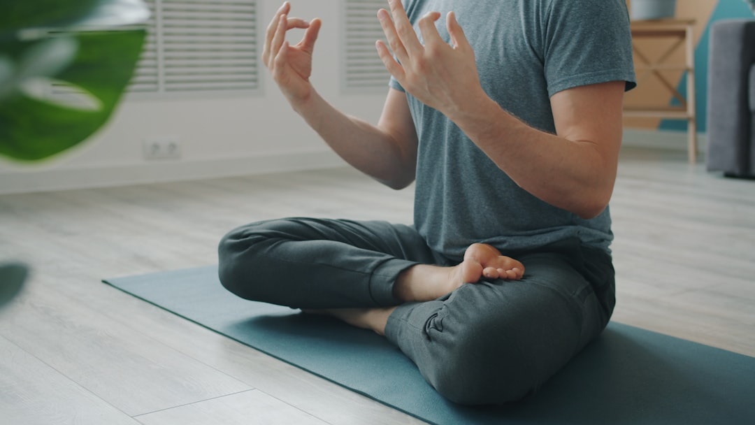 A man seated on a mat performing breathwork as part of a restorative yoga sequence for fatigue