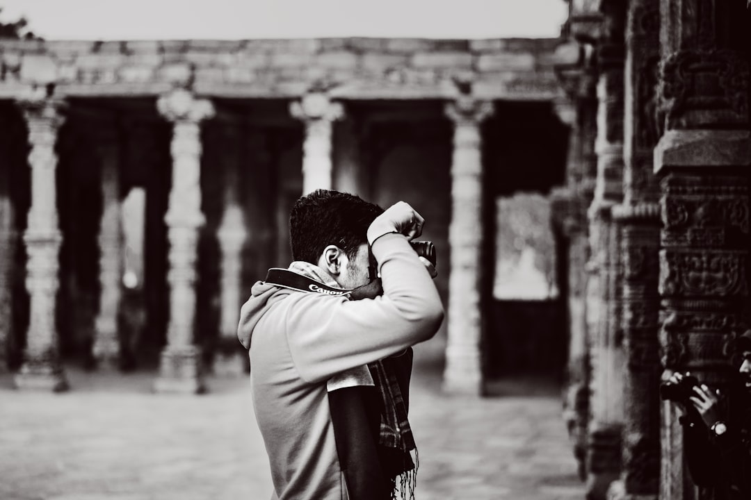 A traveller photographs the archways and stone corridors of an ancient stepwell in India, soft shadows framing the stonework