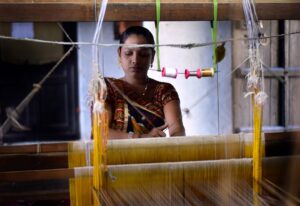 A skilled woman artisan weaving handwoven silk sarees on a traditional loom in India