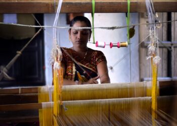 A skilled woman artisan weaving handwoven silk sarees on a traditional loom in India