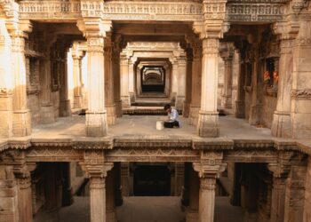 A woman descends the intricate stone steps of one of India's ancient stepwells in Rajasthan in golden morning light